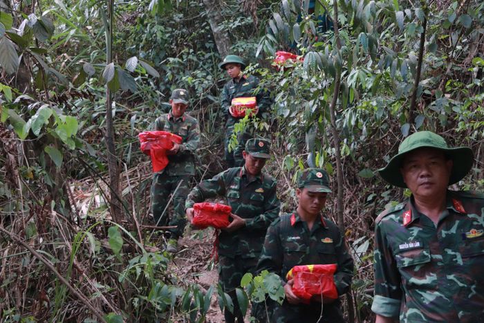 Lực lượng chức năng băng rừng, đưa hài cốt liệt sĩ quy tập được tại hang Đá Sập về an táng. Ảnh: HOÀI SƠN
