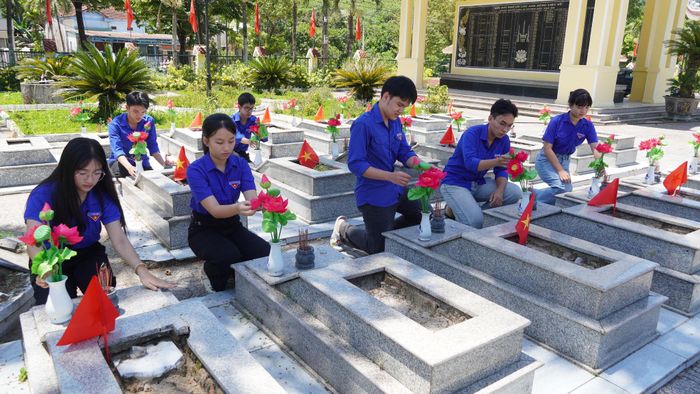 Đoàn viên thanh niên xã Trà My chăm sóc các phần mộ liệt sĩ tại Nghĩa trang liệt sĩ xã Trà My. Ảnh: D.LỆ