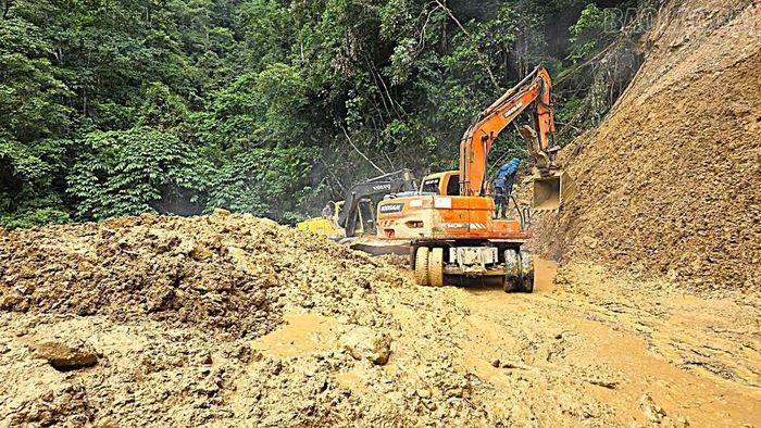 Máy xúc khắc phục tại những vị trí sạt lở rất nguy hiểm.