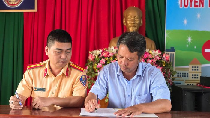 Đại diện Phòng CSGT Công an tỉnh Đắk Lắk và lãnh đạo Nông trường Cư M'gar ký cam kết chấp hành nghiêm các quy định của pháp luật về TTATGT. Ảnh: Ngọc Hùng