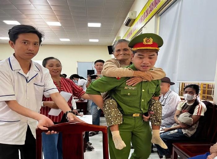 Những người lớn tuổi đi lại khó khăn được cán bộ Công an cõng vào khu vực thu nhận mẫu ADN.