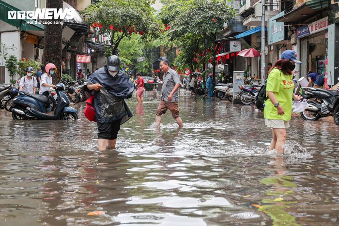 Người dân chật vật đi lại qua khu vực dềnh nước trên phố Hòe Nhai.