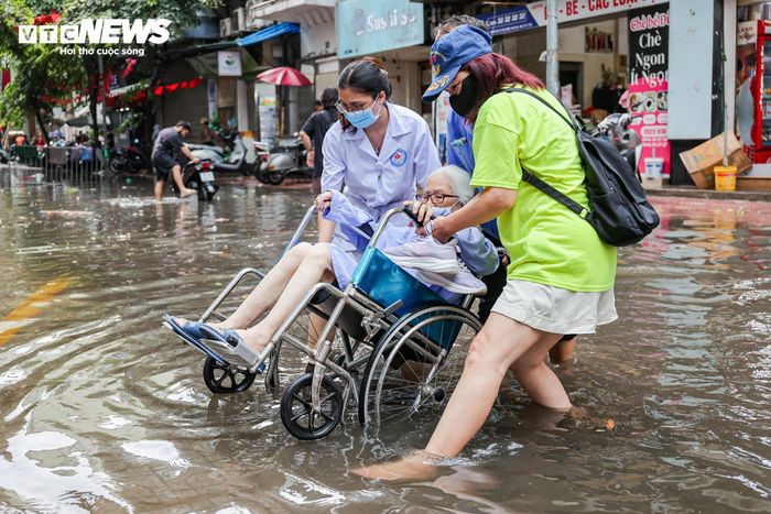 Các bác sĩ và nhân viên Bệnh viện Hòe Nhai vất vả đưa bệnh nhân di chuyển qua đoạn đường dềnh nước.