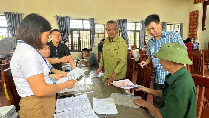 Cán bộ Ban Quản lý dự án Đầu tư - Hạ tầng xã Thường Tín hướng dẫn người dân hoàn thiện thủ tục nhận tiền bồi thường. Ảnh: PV