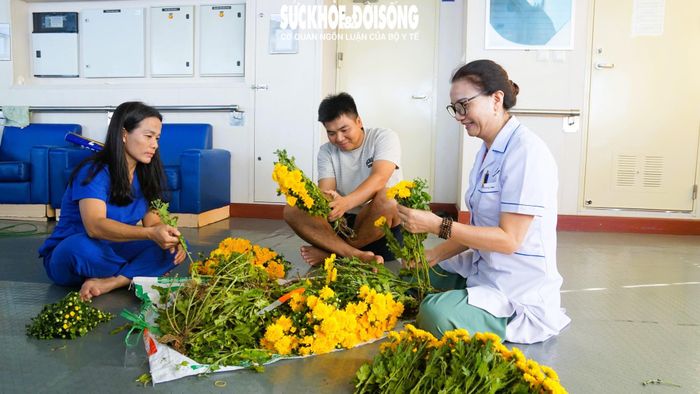 Điều dưỡng Minh Phương (áo trắng) cùng thành viên đoàn công tác tia từng nhành hoa chuẩn bị cho mâm lễ. Ảnh: ML