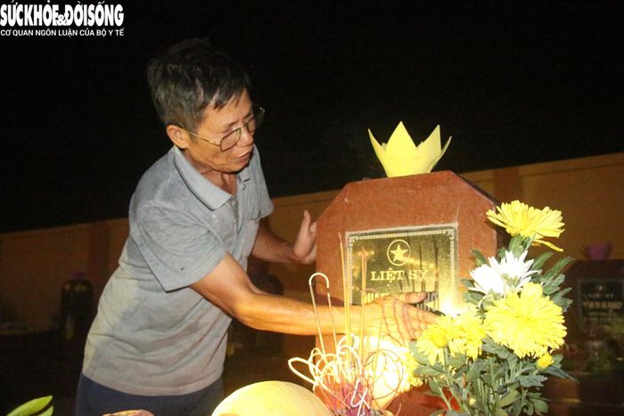 Người đàn ông lặng lẽ lau mặt bia liệt sĩ của gia đình. Ảnh: ĐT