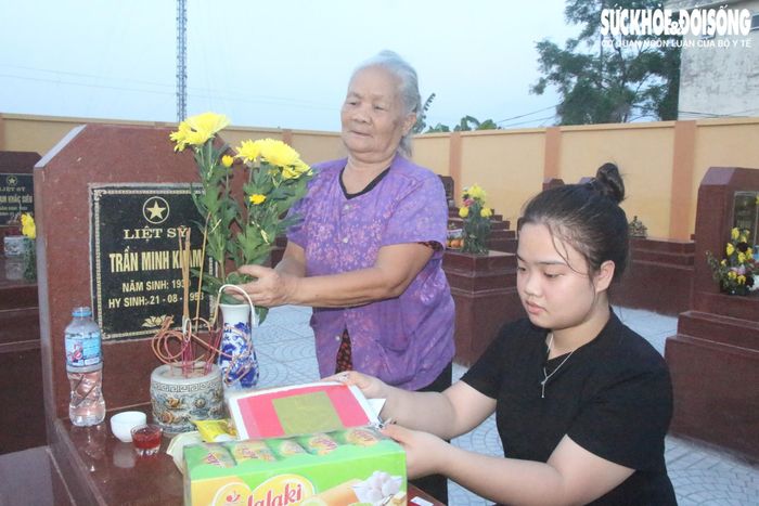Bà Phòng và cháu nội chăm sóc phần mộ liệt sĩ người thân. Ảnh; ĐT