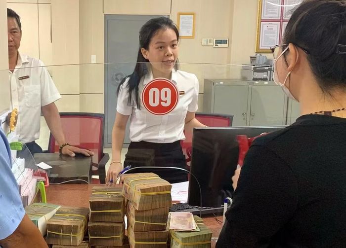 Người dân và nhân viên ngân hàng đang trao đổi để làm thủ tục chi trả tiền bồi thường. (Ảnh: LÊ ĐÌNH THÌN)