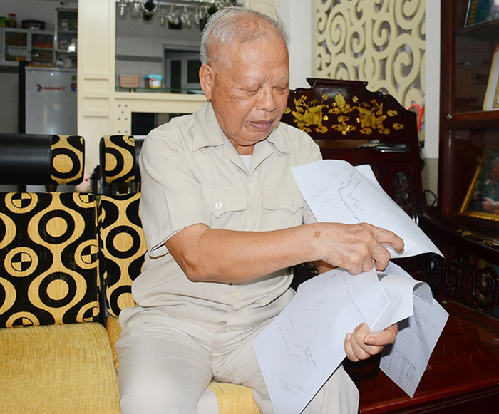 Thiếu tướng Nguyễn Ngọc Doanh xem lại những tư liệu, hình vẽ về vị trí an táng liệt sĩ năm xưa. 