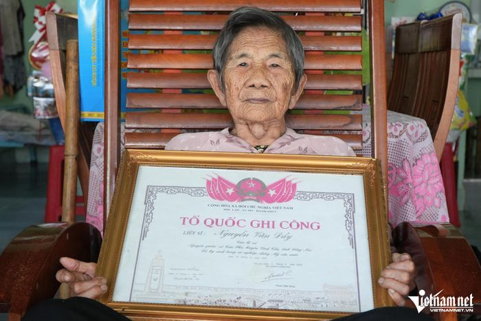 Mẹ Việt Nam Anh hùng Hồ Thị Vàng bên tấm bằng Tổ quốc ghi công của chồng là liệt sĩ Nguyễn Văn Đầy.