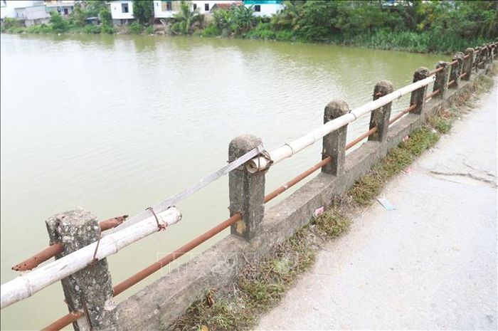 Những đoạn lan can của cầu bị hỏng, gãy được thay thế, cột tạm bằng những thân tre, thanh gỗ. Ảnh: Xuân Tiến/TTXVN