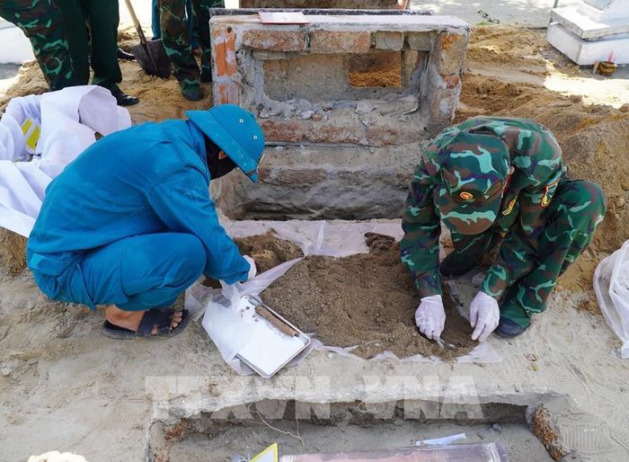 Nhân viên Đội lấy mẫu số 5, Bộ chỉ huy Quân sự tỉnh Quảng Ngãi lấy mẫu sinh phẩm hài cốt liệt sĩ tại Nghĩa trang liệt sĩ Đức Minh, xã Mỏ Cày. Ảnh: Lê Phước Ngọc/TTXVN