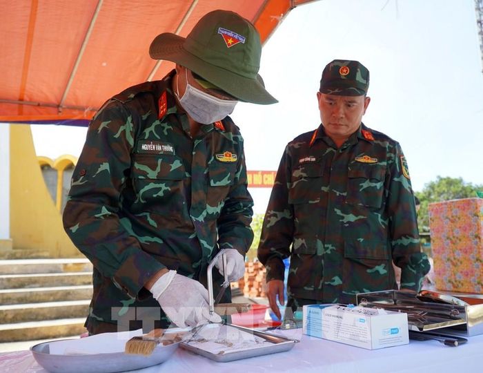 Lực lượng chức năng kiểm tra mẫu sinh phẩm sau khai quật hài cốt liệt sĩ. Ảnh: Lê Phước Ngọc/TTXVN