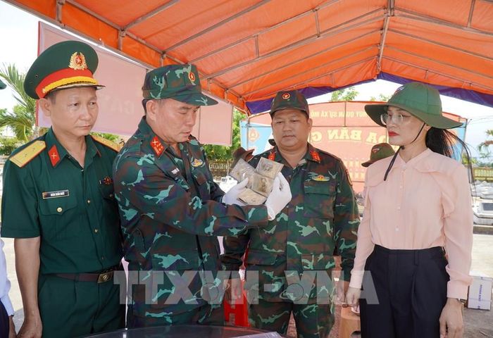 Rà soát, thống kê số lượng di vật tìm thấy tại mộ phần số 115, Nghĩa trang liệt sĩ Đức Minh, xã Mỏ Cày. Ảnh: Lê Phước Ngọc/TTXVN 