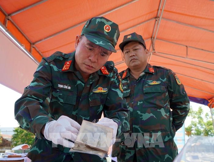 Rà soát, thống kê số lượng di vật tìm thấy tại mộ phần số 115, Nghĩa trang liệt sĩ Đức Minh, xã Mỏ Cày. Ảnh: Lê Phước Ngọc/TTXVN 