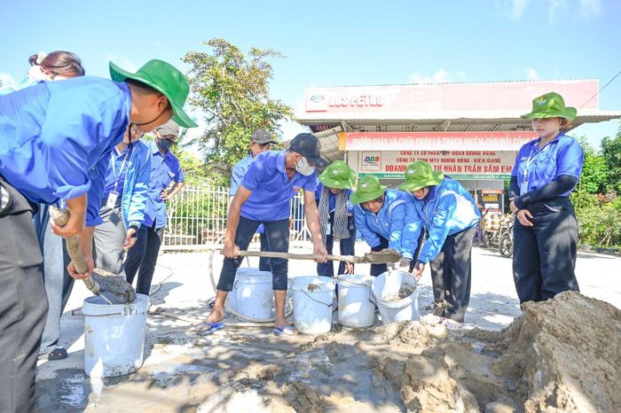 Chiến sĩ tình nguyện cùng đoàn viên, thanh niên địa phương trộn bê tông, dựng cột cờ.