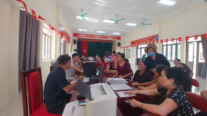 Cán bộ, công chức hỗ trợ người dân làm thủ tục hành chính tại nhà văn hóa thôn ở xã Phượng Dực. Ảnh: Vũ Thoa