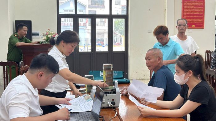 Người dân thôn Yên Phú nhận tiền chi trả, bồi thường GPMB dự án đầu tư xây dựng Khu đô thị thể thao Quốc tế Hà Nội chiều 28-7. Ảnh: PV