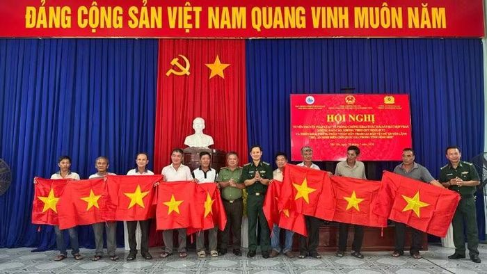Ban tổ chức trao cờ Tổ quốc cho các ngư dân tham dự hội nghị. (Ảnh: Thùy Dung)