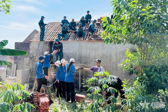 Bộ đội, dân quân phối hợp cùng đoàn viên thanh niên giúp các nạn nhân nhiễm chất độc hóa học xây dựng nhà ở. Ảnh: HOA LÊ