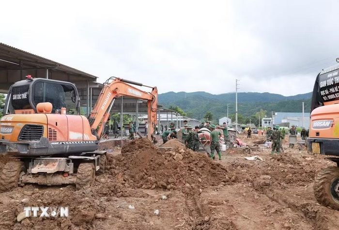 Máy xúc san gạt nền nhà thi công tại bản Sân Bay, xã Mường Than. (Ảnh: Quý Trung/TTXVN)