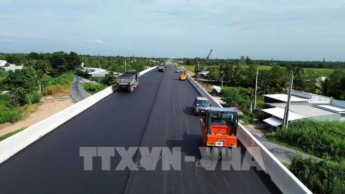 Tranh thủ thời tiết thuận lợi, đơn vị thi công tiến hành thảm nhựa cầu Kênh Xáng. Ảnh: Công Trí - TTXVN