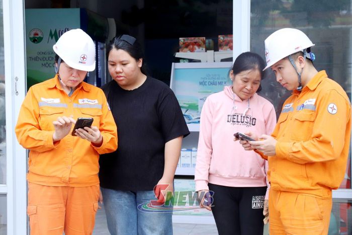 Công nhân Điện lực Phù Yên - Bắc Yên hướng dẫn hộ kinh doanh thanh toán tiền điện không dùng tiền mặt.