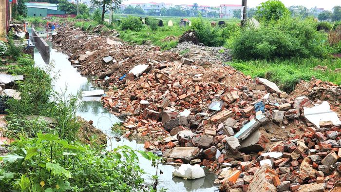 Đất nền đường đào đi nơi khác, nhà thầu đổ trạc thải xây dựng vào nhưng không san lấp khiến cuộc sống của nhiều hộ dân thôn Đại Lâm đảo lộn.