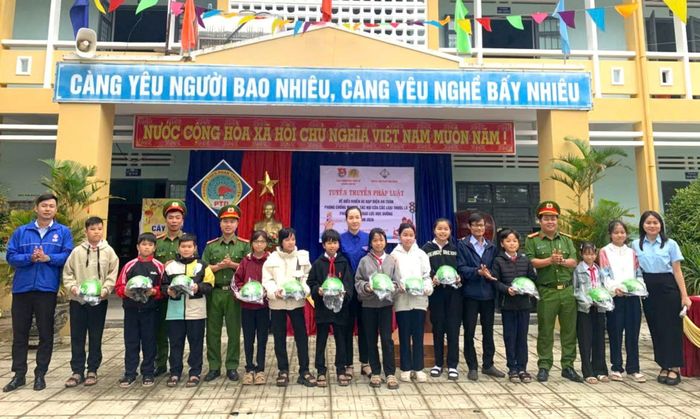 Cán bộ Công an xã Điện Bàn Tây trao mũ bảo hiểm tặng các em học sinh tại buổi tuyên truyền pháp luật về trật tự, an toàn giao thông và phòng, chống ma túy.