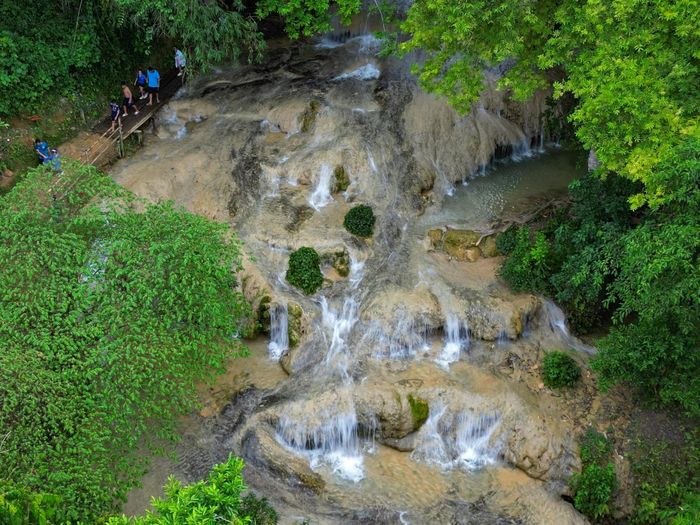 Từ xa nhìn lại, dòng thác trắng xóa uốn lượn mềm mại như dải lụa hay những tầng mây vắt ngang sườn núi. Tiếng nước chảy hòa cùng màu xanh của rừng già, những tán cây cổ thụ và không khí mát lạnh quanh năm tạo nên một không gian trong lành. Ảnh: Đình Minh