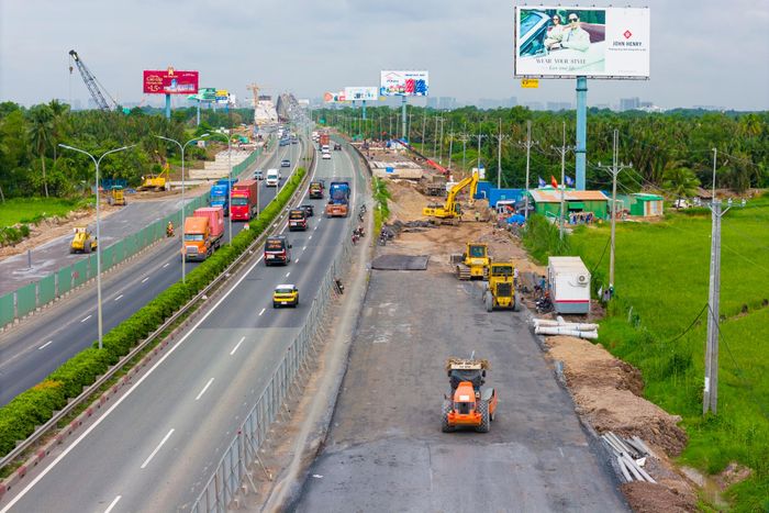 Cạnh dòng phương tiện lưu thông liên tục trên tuyến cao tốc TP.HCM - Long Thành, hàng trăm kỹ sư, công nhân cùng máy móc đang ngày đêm tăng tốc thi công các hạng mục mở rộng tuyến đường.