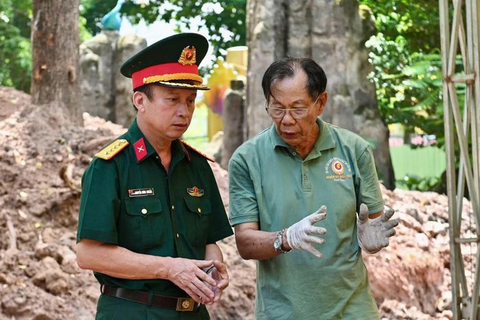  Đại tá Nguyễn Đình Chuẩn, Phó Chính ủy Bộ Tư lệnh TP.HCM, trao đổi công tác tìm kiếm cùng bác sĩ quân y Trần Văn Bản - tình nguyện viên đặc biệt đang tham gia hỗ trợ phân loại, lấy mẫu hài cốt liệt sĩ tại công viên Lê Thị Riêng. 
