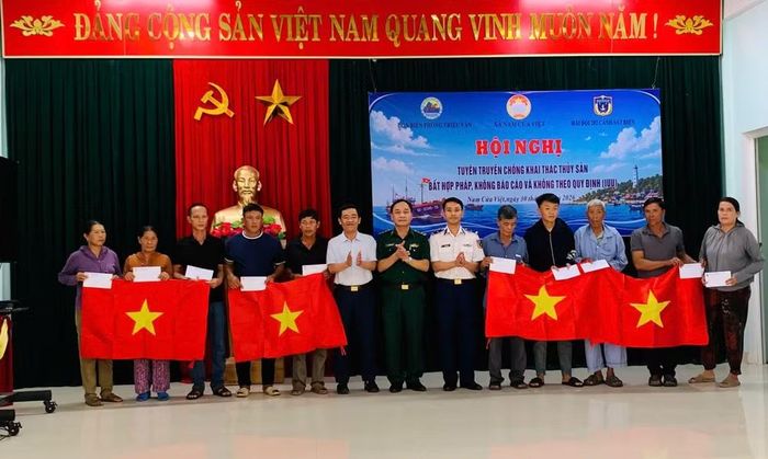 Ban tổ chức trao quà và cờ Tổ quốc cho ngư dân có hoàn cảnh khó khăn tại buổi tuyên truyền chống khai thác IUU. (Ảnh: XUÂN THẾ)