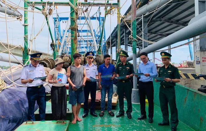 Các đơn vị tuyên truyền, phát tờ rơi trên các tàu cá đang neo đậu tại Cảng Nam Cửa Việt. (Ảnh: XUÂN THẾ).