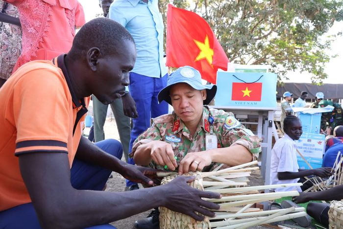 Cán bộ, nhân viên Bệnh viện dã chiến cấp 2 số 7 hướng dẫn người dân đan giỏ từ cây bồn bồn. (Ảnh: TIẾN PHÚC)