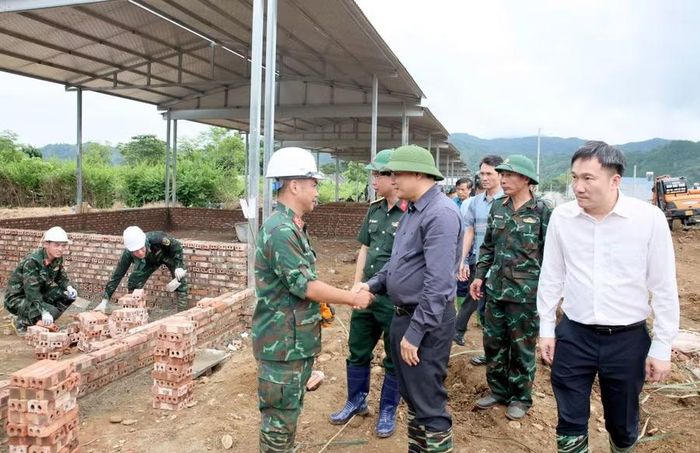 Ông Lê Minh Ngân, Bí thư Tỉnh ủy Lai Châu (áo xám) động viên cán bộ, chiến sĩ Bộ Chỉ huy Quân sự tỉnh Lai Châu đang xây dựng nhà ở tại khu tái định cư.