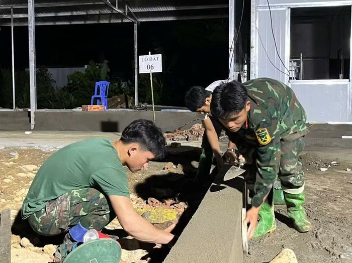 Dưới ánh đèn cao áp, cán bộ chiến sĩ vẫn miệt mài, tỉ mỉ để xây nhà cho người dân vùng lũ.