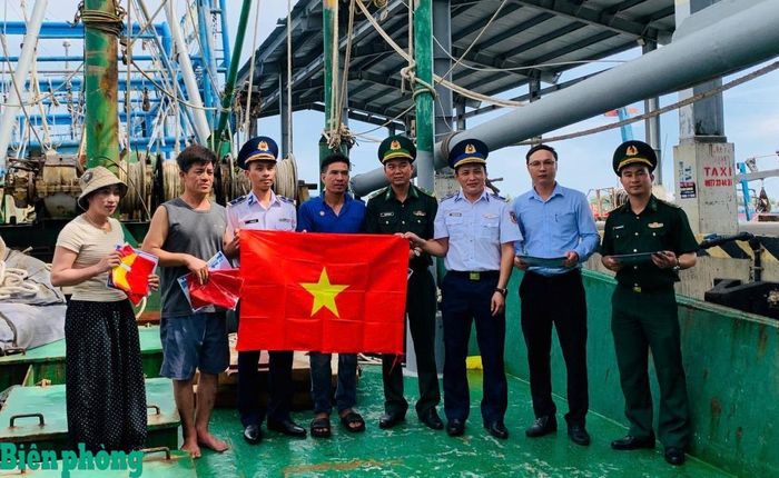 Cán bộ các đơn vị tuyên truyền chống khai thác IUU và trao tặng cờ Tổ quốc cho các chủ tàu thuyền tại cảng cá Nam Cửa Việt. Ảnh: Xuân Thế