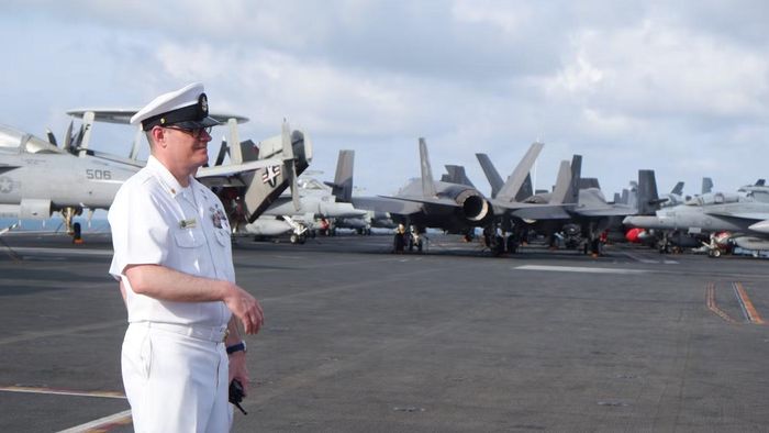 Một sĩ quan làm việc hướng dẫn khách tham quan khu vực đường băng trên tàu sân bay USS George Washington.