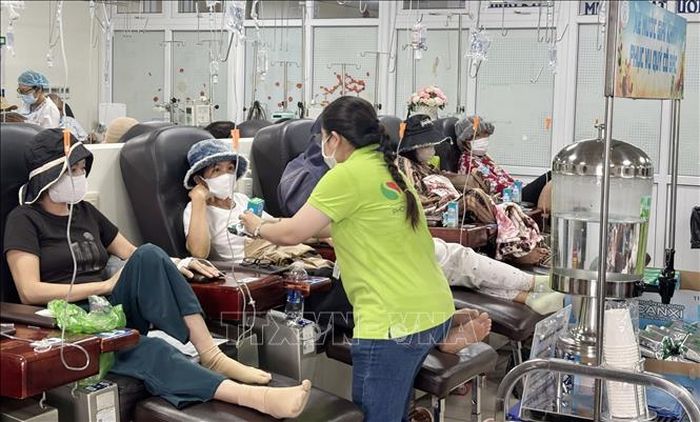 Nhân viên công tác xã hội phục vụ miễn phí bánh, sữa cho bệnh nhân ung thư tại Khu Hóa trị của Bệnh viện Chợ Rẫy. Ảnh: Đinh Hằng/TTXVN