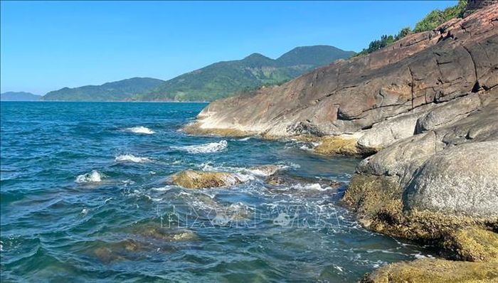 Những hòn đá xám sẫm nằm rải rác dưới chân núi Hải Vân, như những mảnh ghép thô ráp của thiên nhiên xen lẫn giữa vẻ đẹp dịu dàng của biển xanh Lăng Cô.
