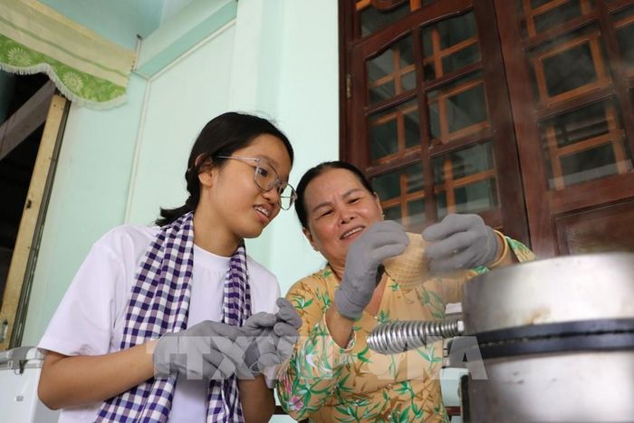 Du khách trải nghiệm làm bánh kẹp xoài tại Di tích Phủ thờ Thư Ngọc Hầu (xã Mỹ Thọ). Ảnh: Hồng Thái - TTXVN