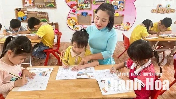 Giáo viên hướng dẫn các cháu luyện viết chữ. Ảnh: Khánh Linh