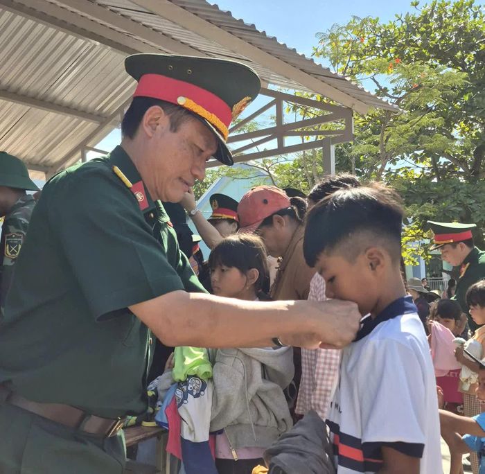 Một em nhỏ được cán bộ Trường Sĩ quan Thông tin hỗ trợ thử đồ tại gian hàng "0 đồng".