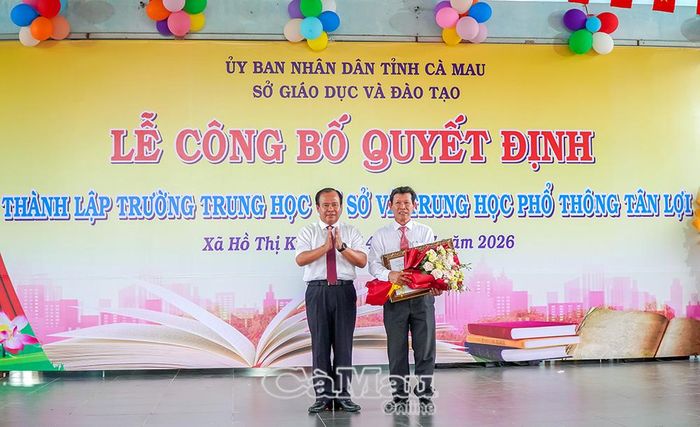 Ông Nguyễn Minh Luân, Ủy viên Ban Thường vụ Tỉnh ủy, Phó Chủ tịch UBND tỉnh (bìa trái), trao Quyết định của UBND tỉnh về việc tổ chức lại Trường THCS Tân Lợi thành Trường THCS và THPT Tân Lợi vào ngày 14/7.