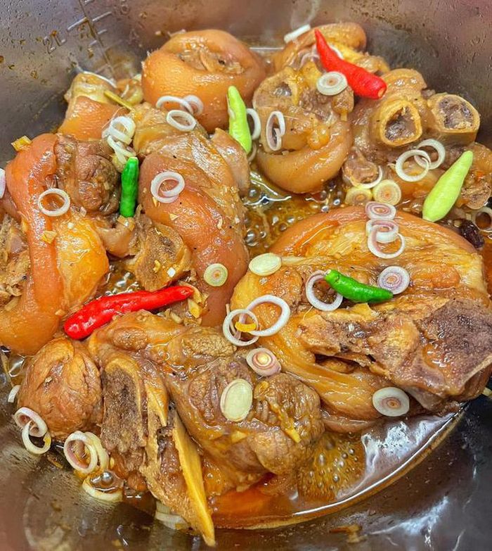 Phi thơm phần hành, tỏi, sả còn lại với một ít dầu ăn, cho thêm 2 – 3 cái hoa hồi vào đảo nhanh cho dậy mùi. Tiếp đến, cho chân giò vào xào săn lại, đổ nước dừa và coca vào ngập mặt thịt là được.Đun sôi rồi sau đó hạ nhỏ lửa, kho khoảng 45-60 phút hoặc có thể dùng nồi áp suất cho ngắn thời gian và nhanh nhừ. Khi nước kho sánh lại, thịt mềm và thấm đều gia vị thì nêm nếm lại cho vừa ăn. Cuối cùng cho ít sả băm, ớt vào để cho món ăn thêm đậm vị và bắt mắt. Ảnh: Đan Vy