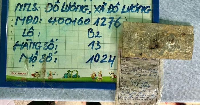 Mảnh nhôm khắc tên Đinh Xuân Tình và phiếu ghi thông tin về liệt sĩ được tìm thấy trong mộ chưa rõ danh tính ở Nghĩa trang liệt sĩ Đô Lương.