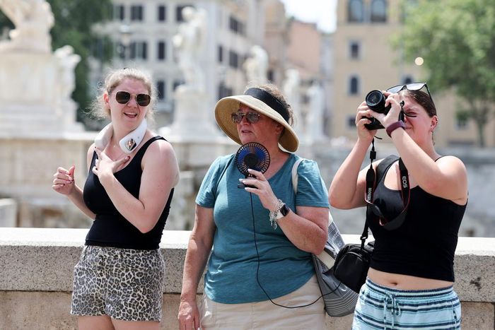 Khách du lịch dùng quạt cầm tay để tránh nóng tại Rome, Italy. Ảnh: THX/TTXVN phát