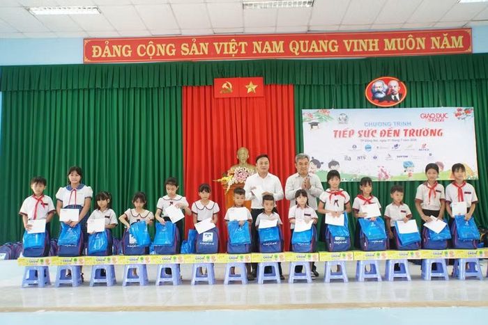Ông Lê Hữu Ái, Tổng giám đốc Công ty Cổ phần đầu tư QAHAN Group (trái) và ông Nguyễn Hùng Hải, Phó Bí thư Đảng ủy, Chủ tịch UBND xã Tà Lài trao quà, học bổng cho học sinh.
