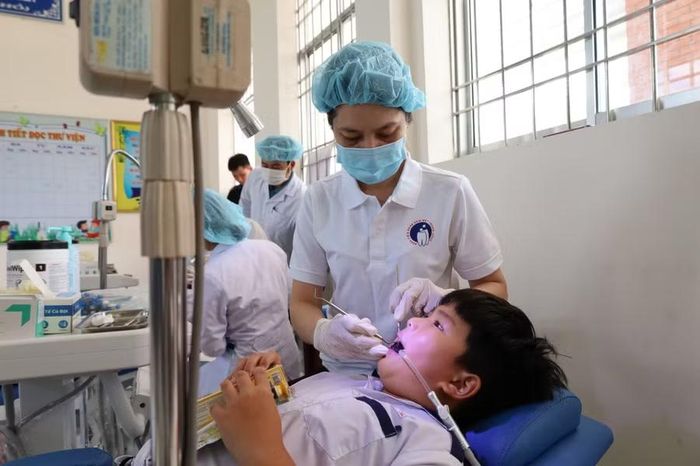 Nhân viên y tế vệ sinh răng miệng cho học sinh.